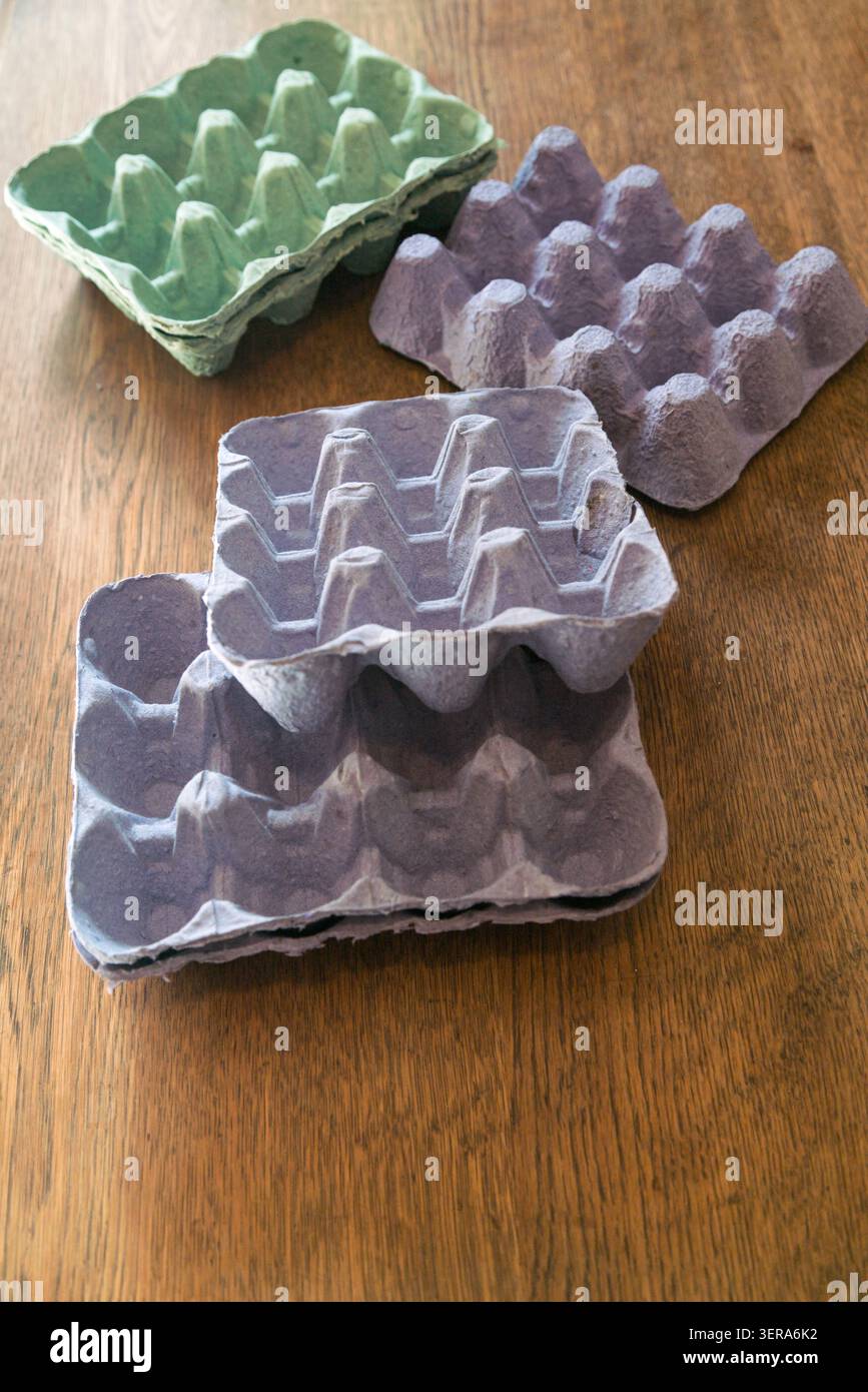 Empty egg cartons made of molded paper pulp, in pastel colors, on a wooden table Stock Photo