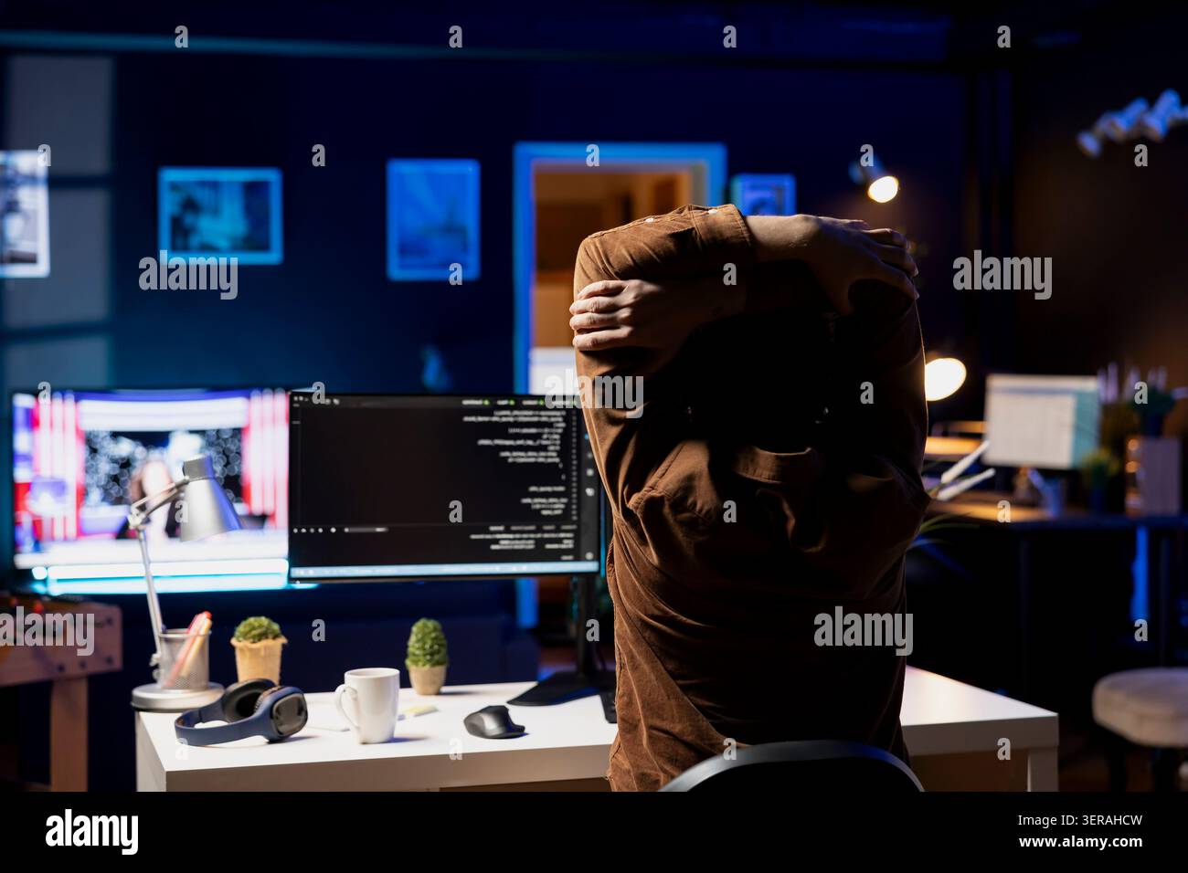 Programmer doing software quality assurance, stretching arms behind back after reading source code, feeling fatigued. IT expert taking break from work to relax muscles after inspecting coding. Stock Photo