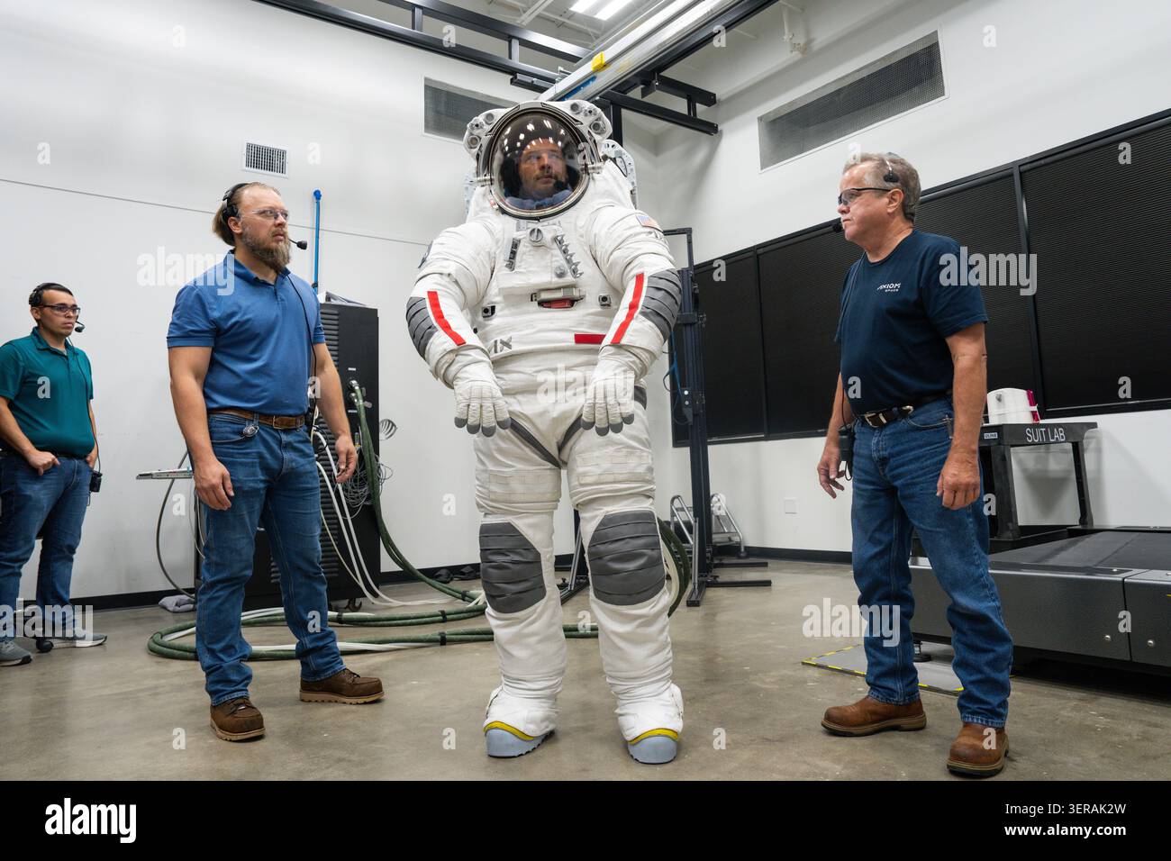 Travis Cooper wears a spacesuit prototype flanked by technicians ...