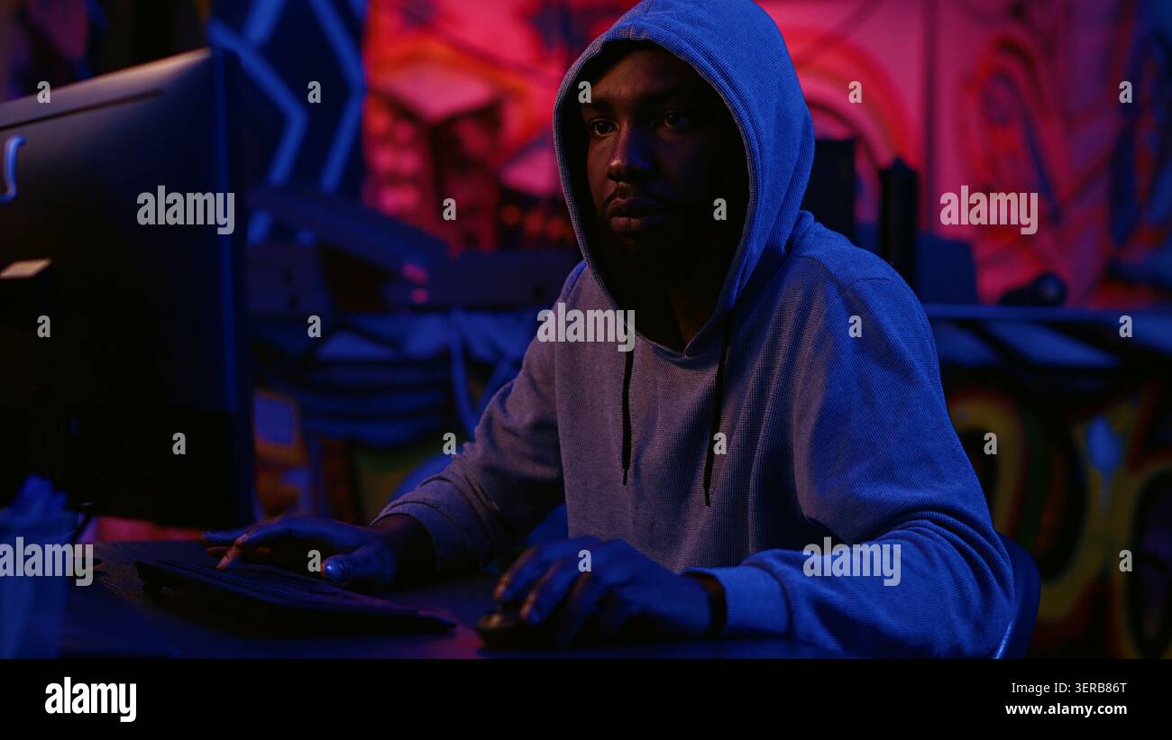 Hacker in secret dark room writing lines of code on computer, developing virus that get past security systems, evil developer uses PC in hidden bunker, running hacking script. Stock Photo