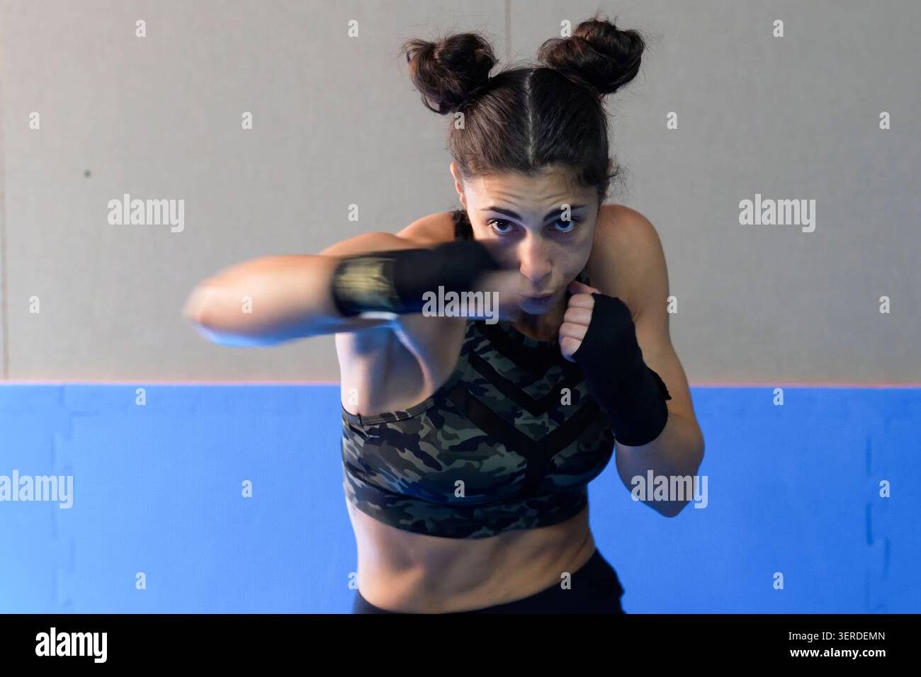 Determined female fighter practicing sharp punches during highenergy workout session inside gym Stock Photo