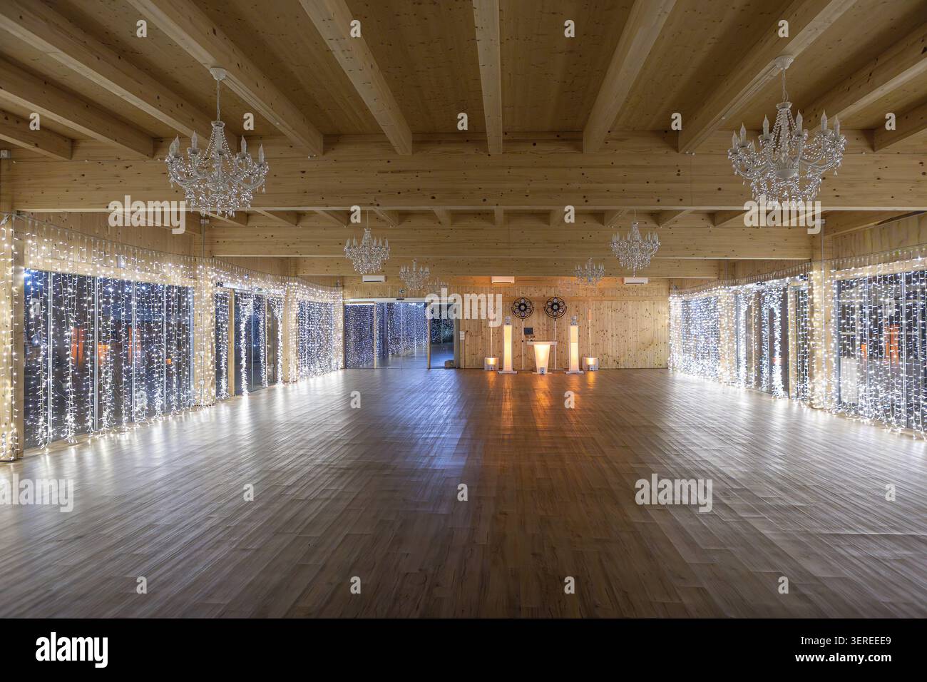 Elegant event hall interior with sparkling fairy lights, chandeliers, and wooden beams Stock Photo