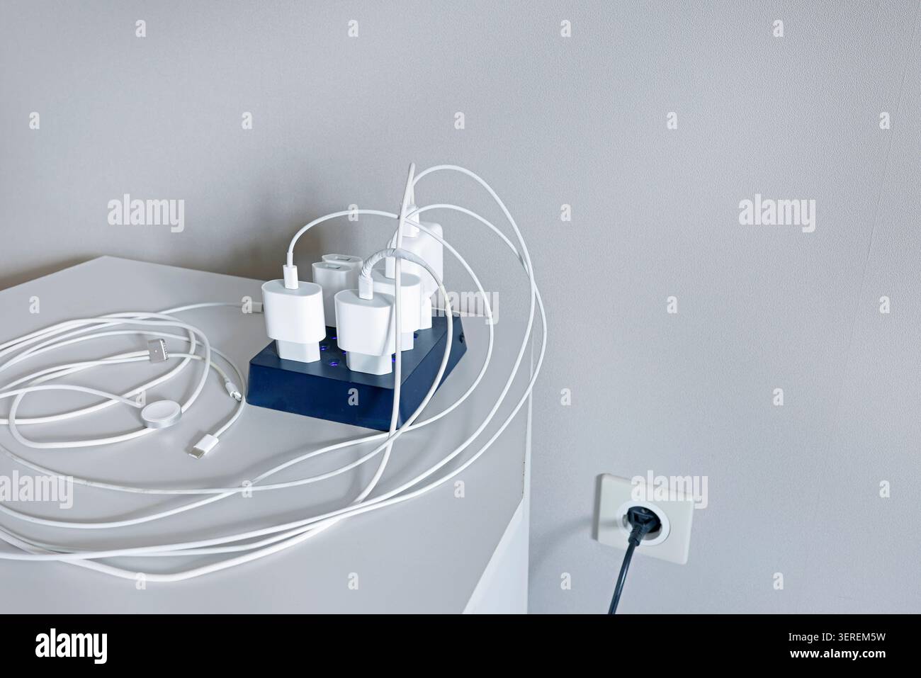Outdated messy charging station with multiple tangled wired power adapters on desk. Daily technology problem showing excessive cable clutter before Stock Photo