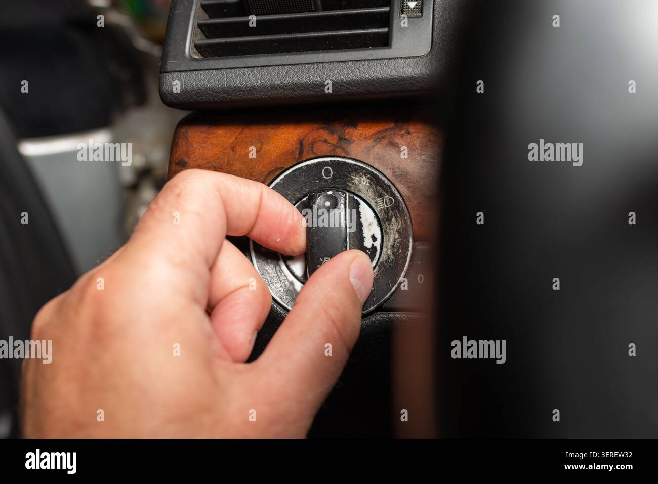 Driver hand operating the headlight control switch in a old car. Stock Photo