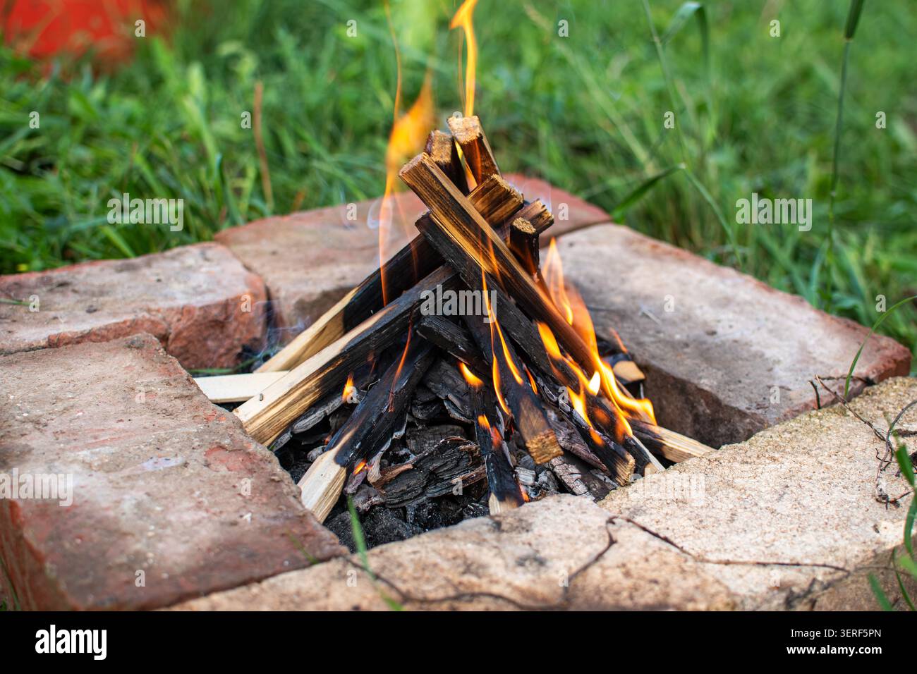 Bonfire flame in handmade brick fire pit outdoors Stock Photo