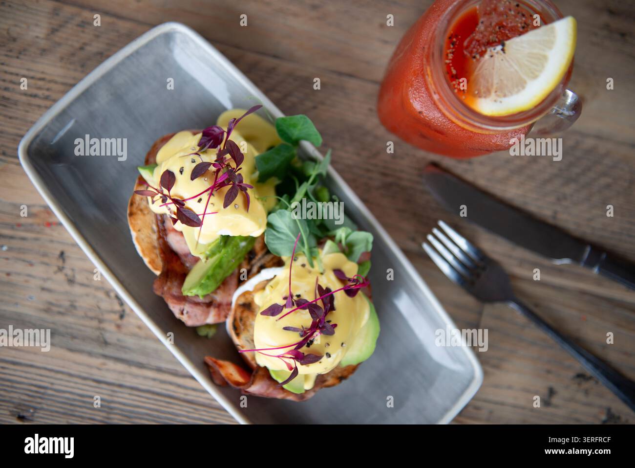 Delicious Brunch Delight With Eggs Benedict and Refreshing Drink Served on Rustic Table Stock Photo