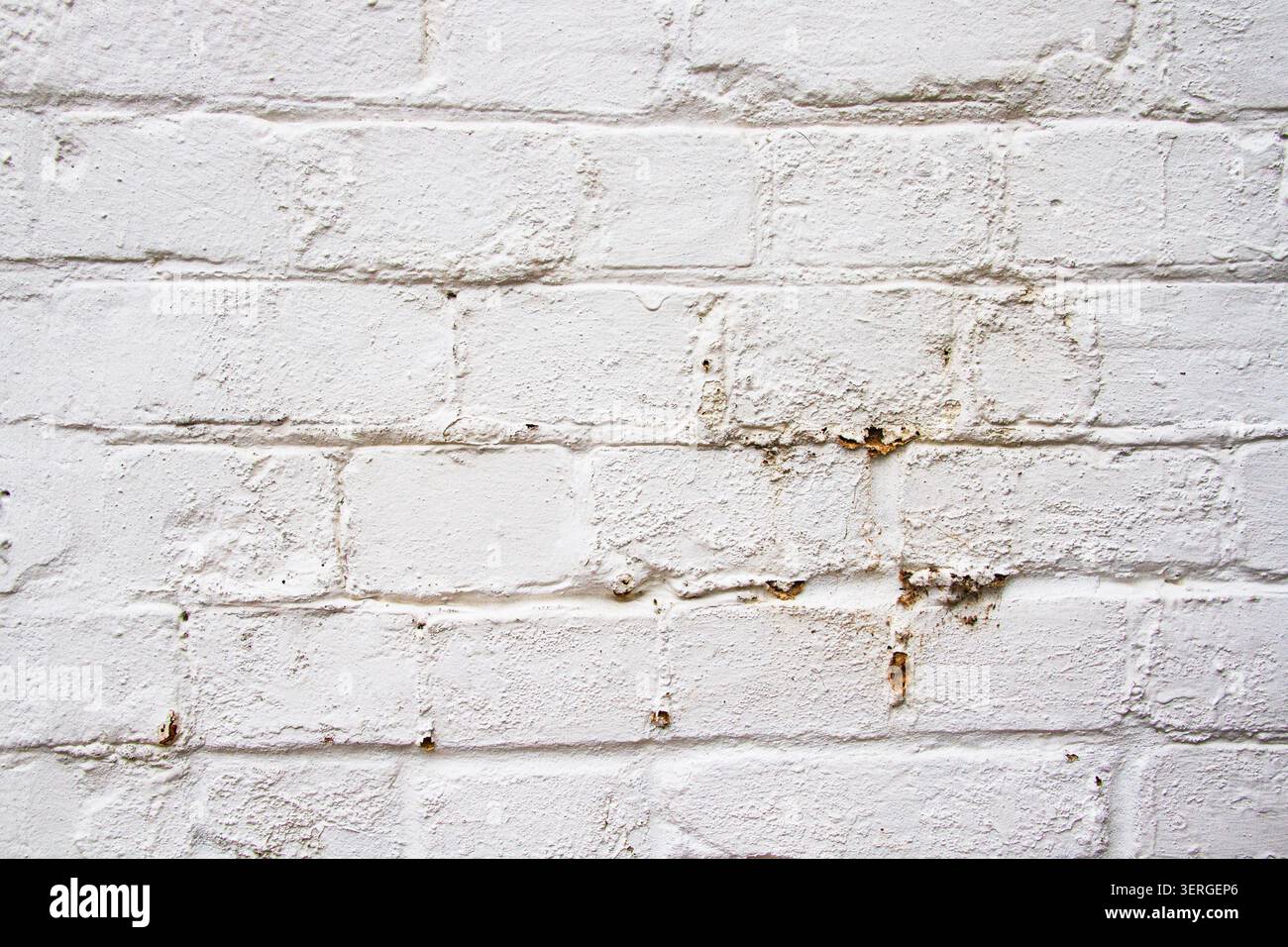 A dirty old white painted brick wall background with rust marks from items previously fixed to it Stock Photo