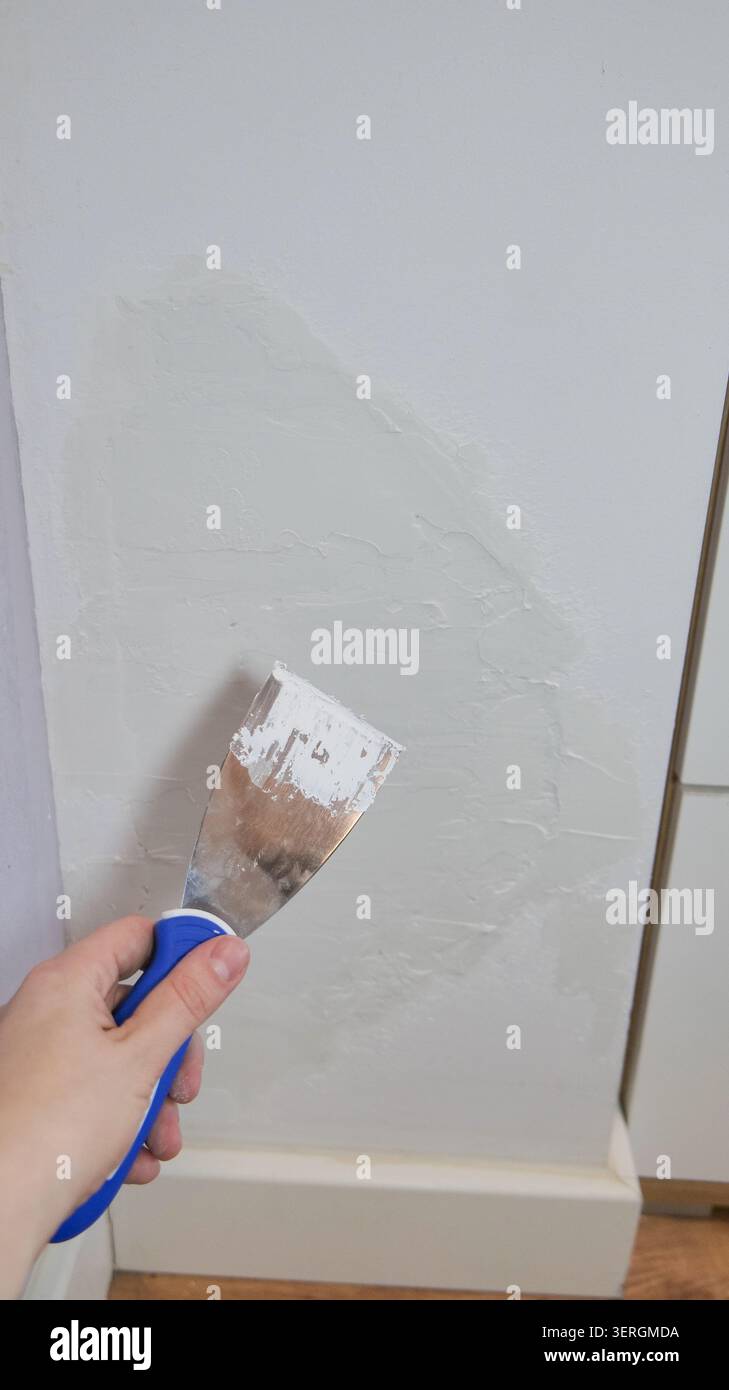 Putty Knife with Plaster Paste on Damaged Wall Stock Photo