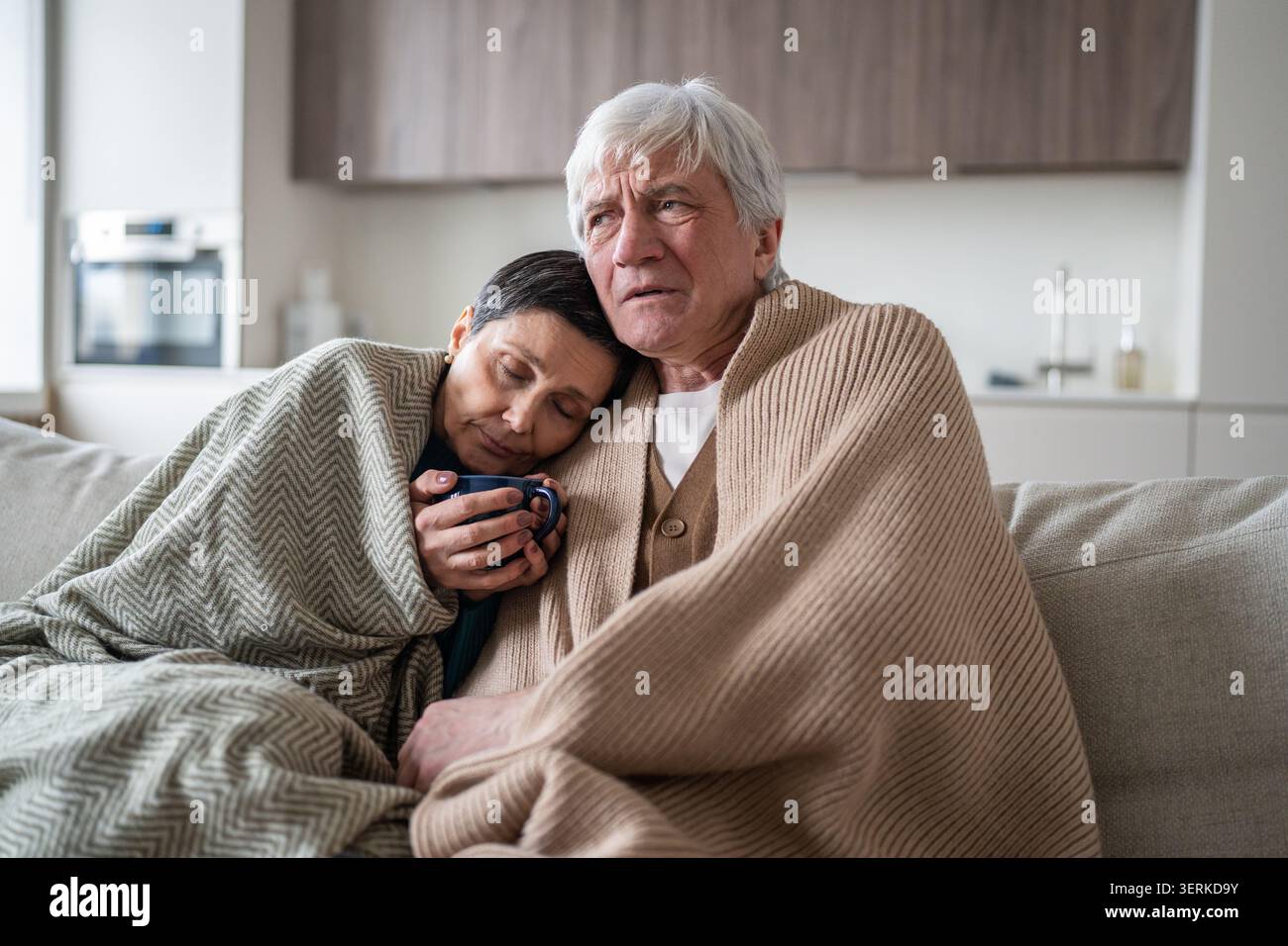 Senior family man and woman sharing cold flu sickness, sitting together on sofa suffering from fever Stock Photo