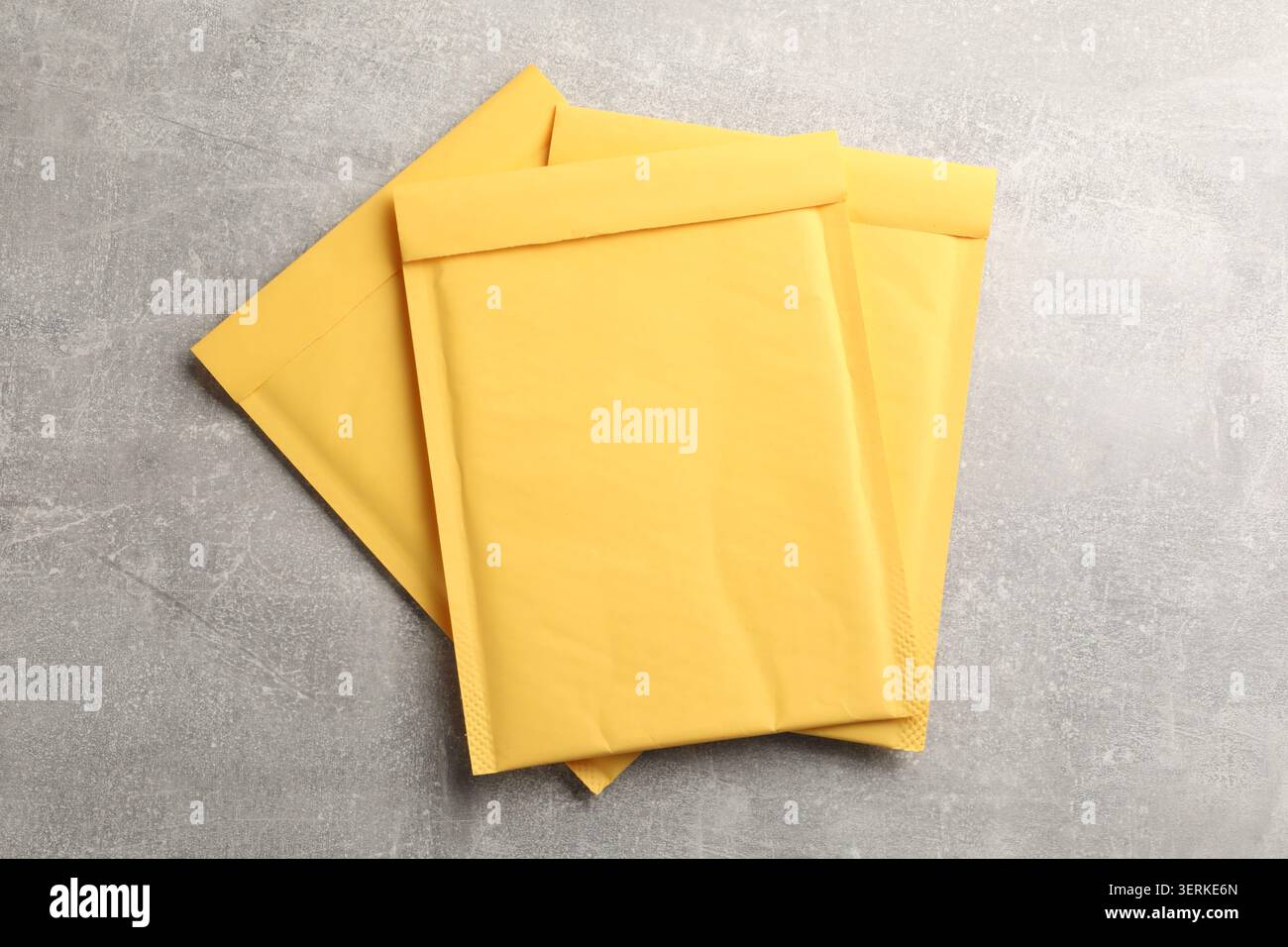 Stack of yellow envelopes on grey table, top view Stock Photo