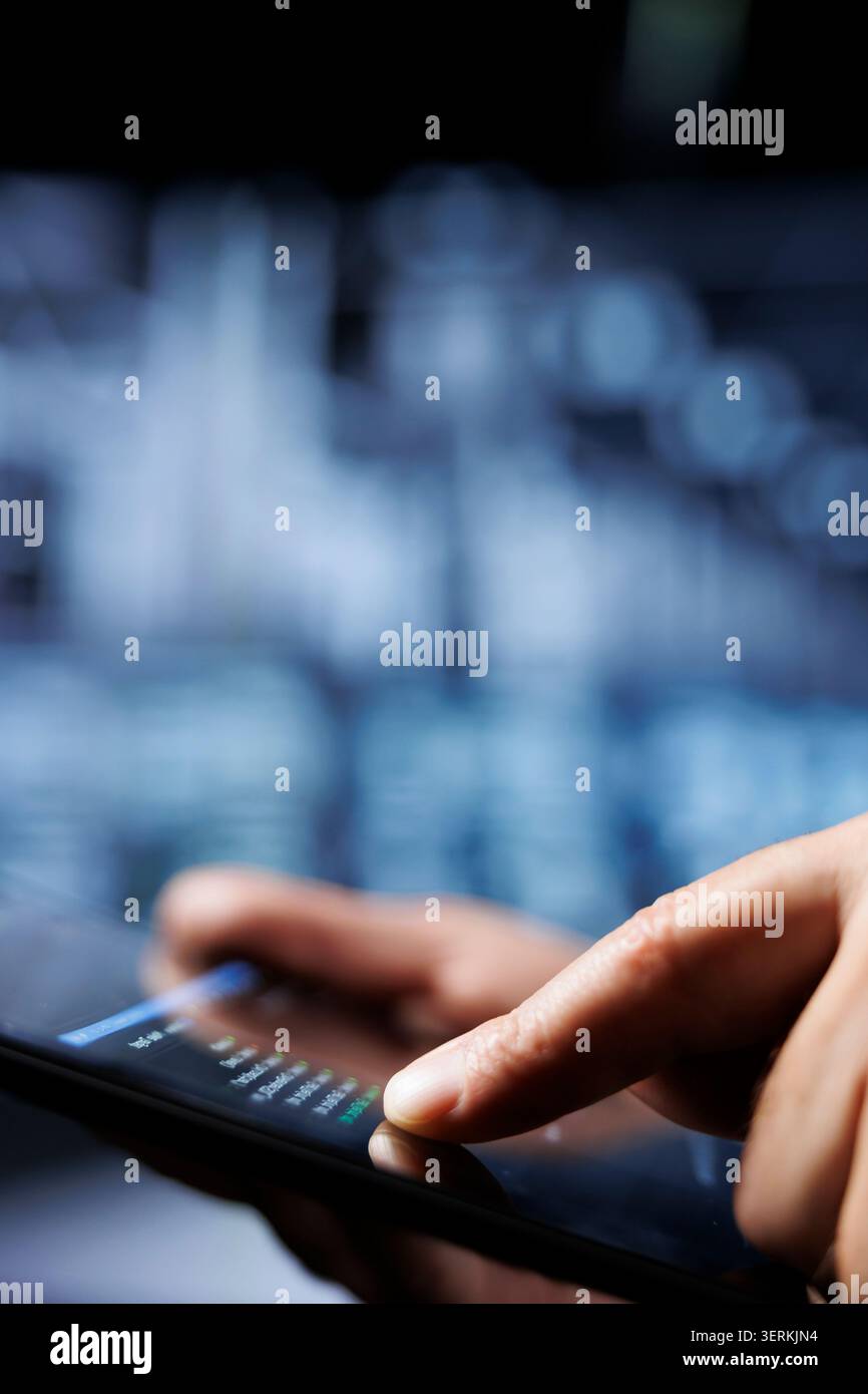 Certified system administrator updates server rigs, writing intricate binary code scripts on tablet. Computer scientist using programming to fortify cybersecurity in high-tech place. Stock Photo