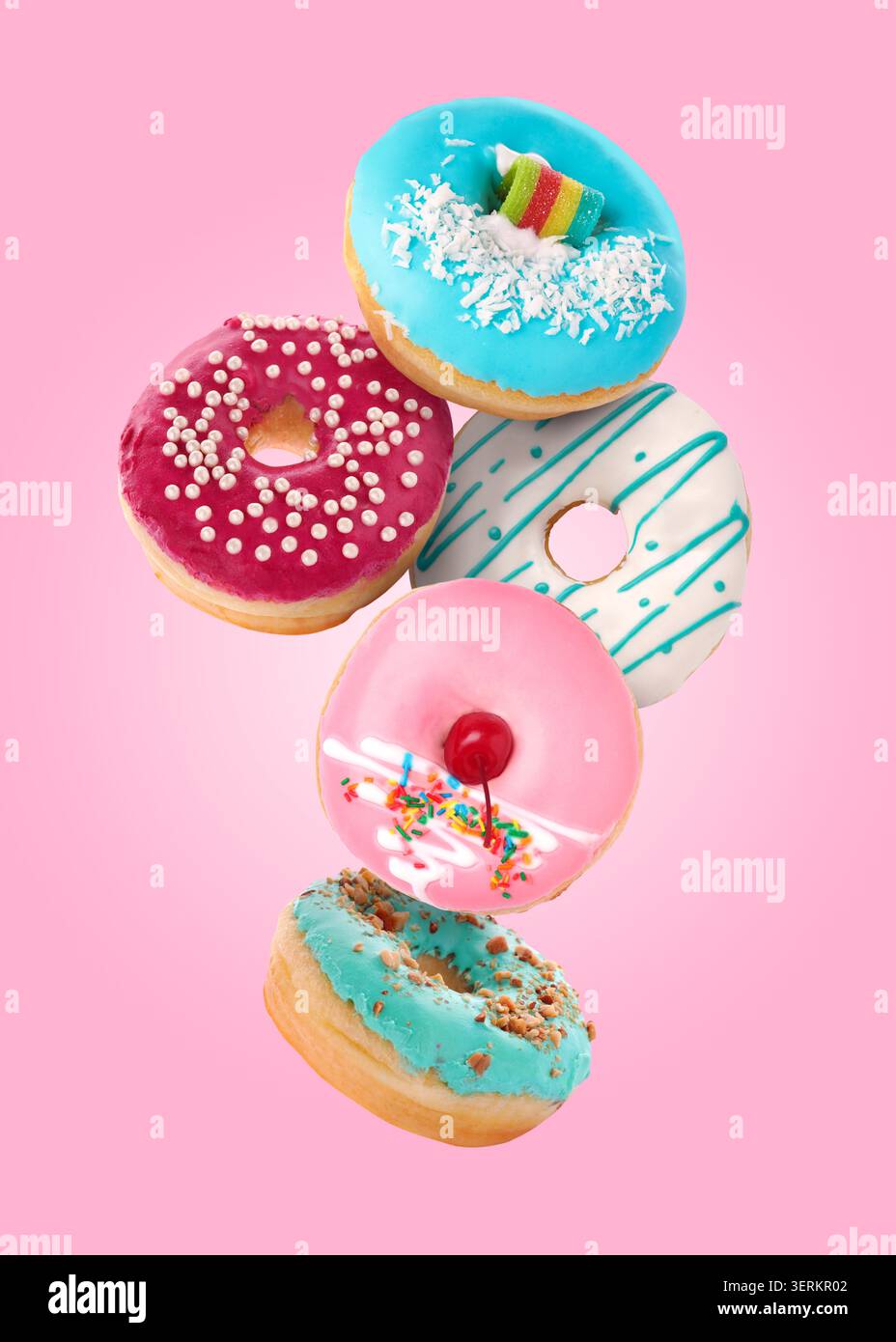 Yummy donuts covered with icing falling on pink background Stock Photo