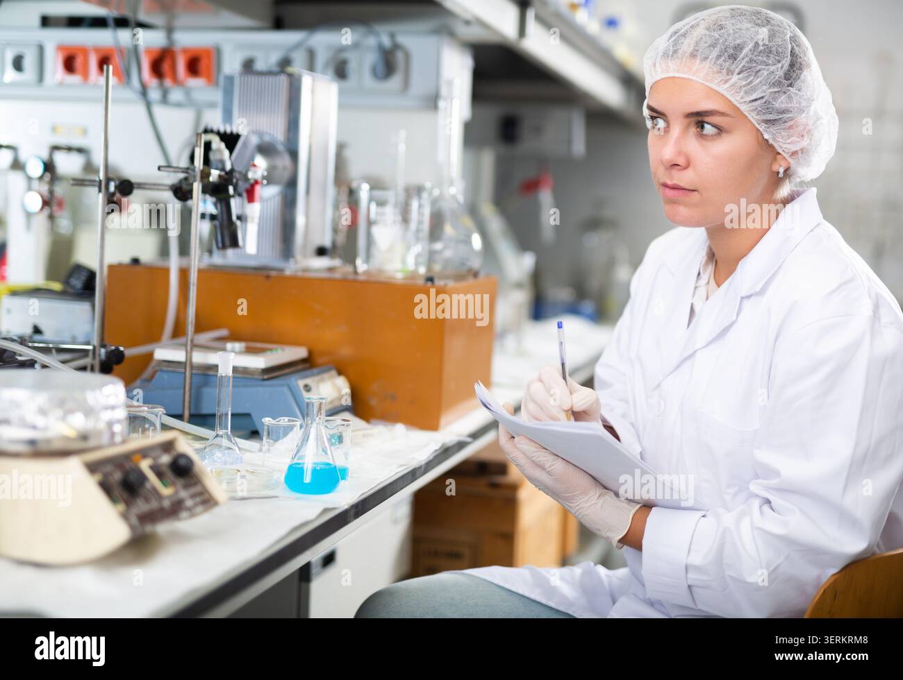 Young woman lab technician working, writing notes Stock Photo