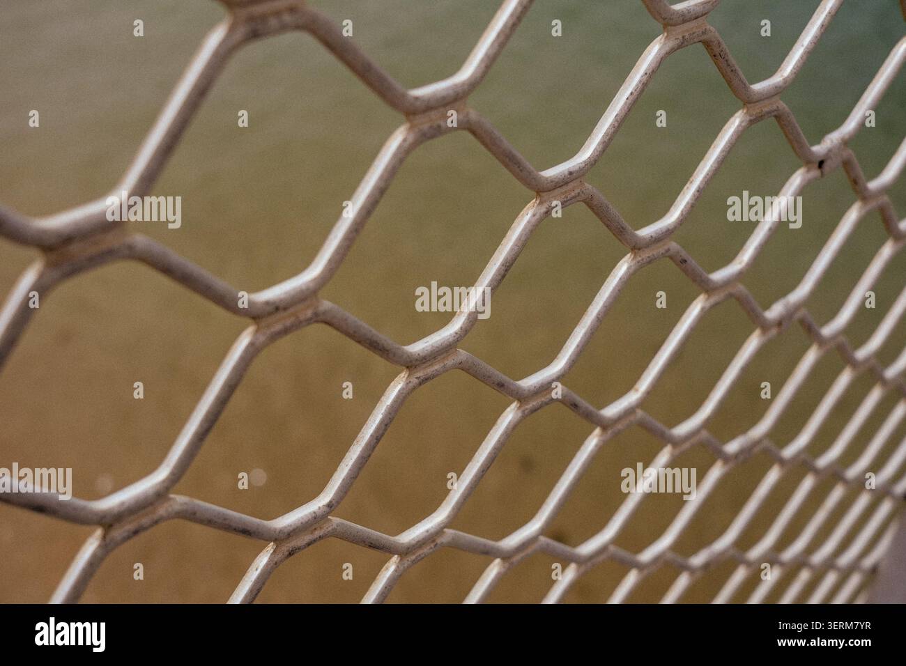 Metal mesh forms repeating hexagonal pattern. Worn surface suggests outdoor use or aging exposure Stock Photo