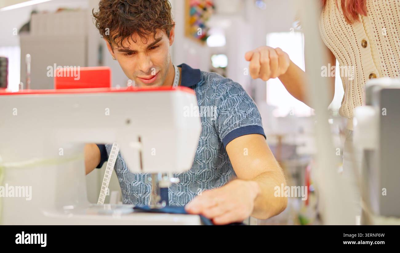 Young man learning sewing in atelier with instructor Stock Photo