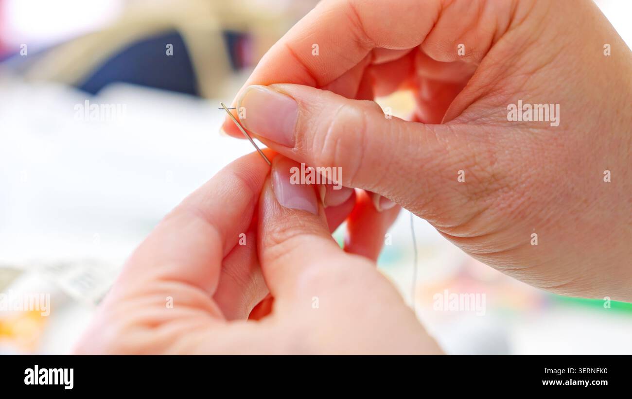 Hands threading needle preparing for sewing crafting workshop Stock Photo
