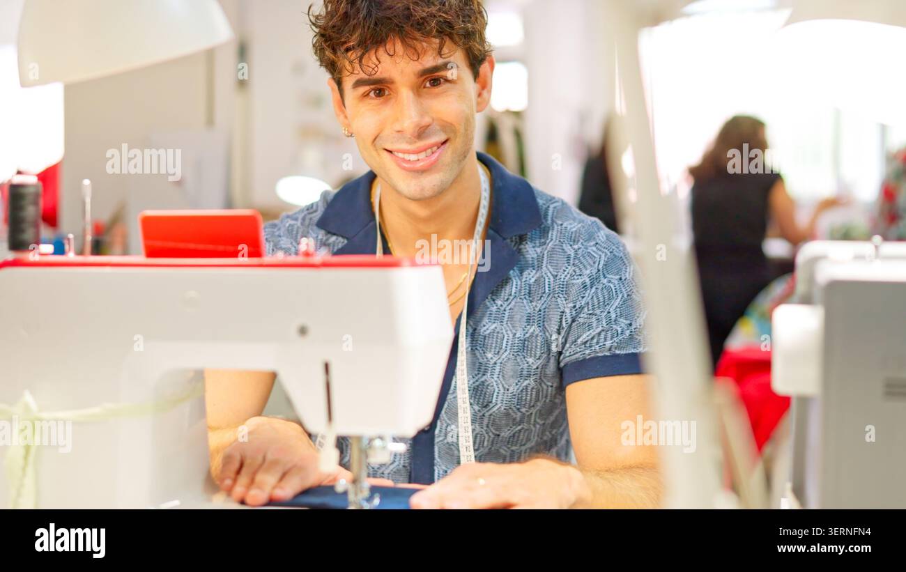 Young tailor smiling while working at sewing workshop Stock Photo
