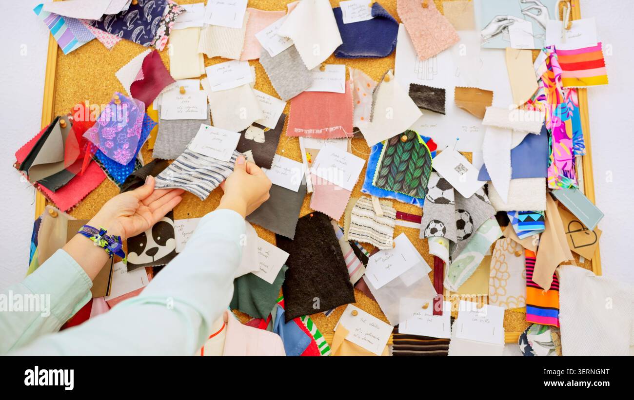 Designer hands choosing fabric swatches on a cork board Stock Photo