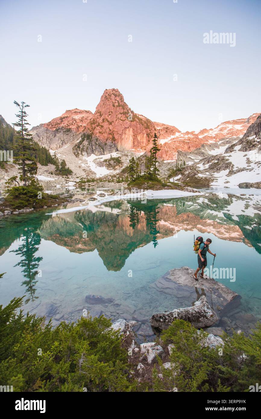 Man explores pristine alpine lake with mountain reflection Stock Photo
