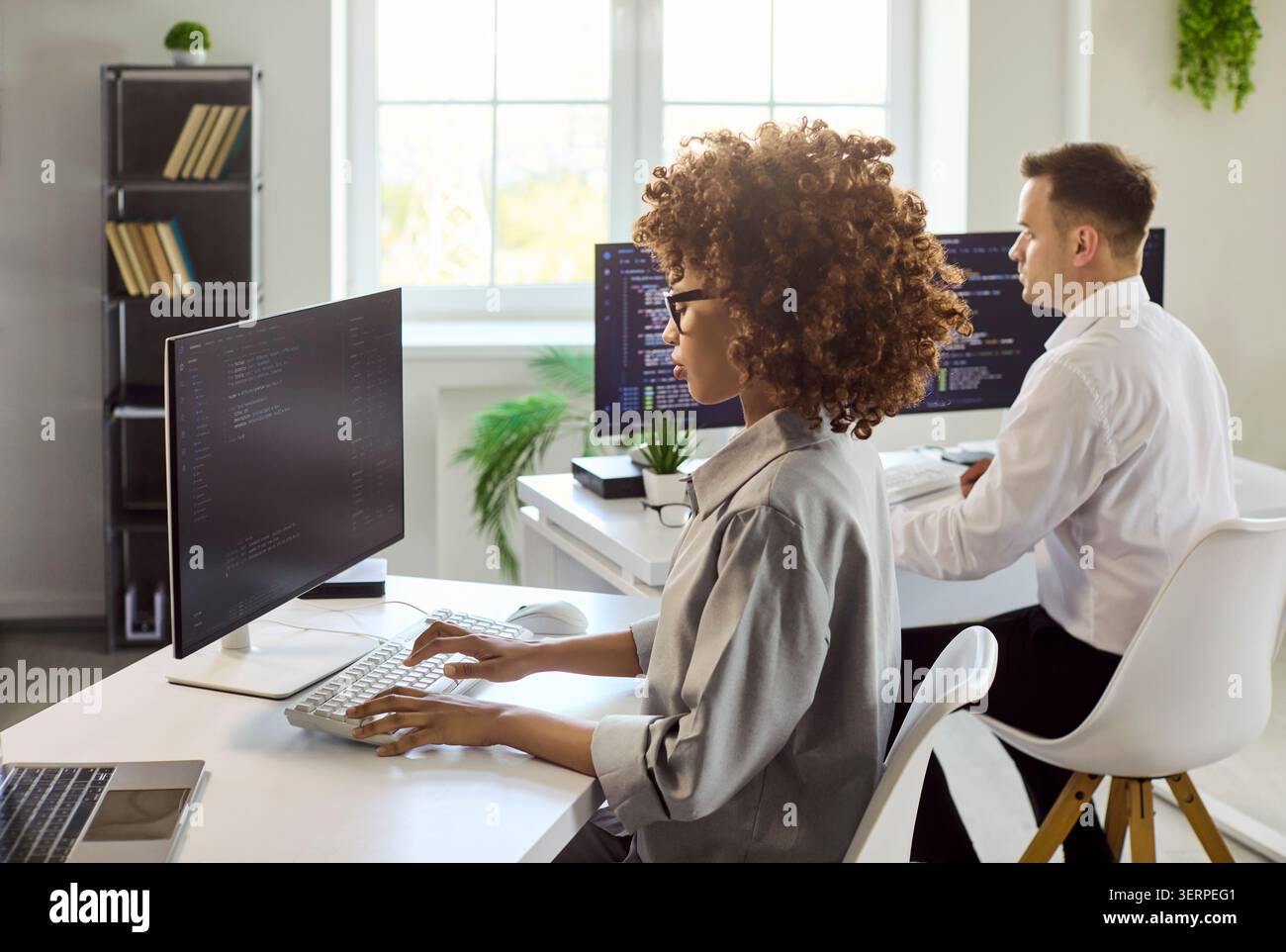 Programmers working on code in bright office, dual monitors and collaboration Stock Photo