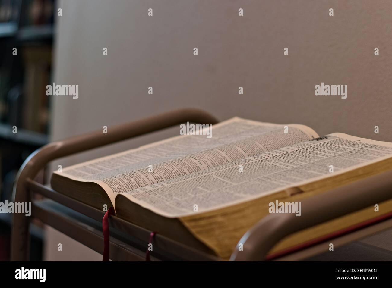 Open dictionary resting on a reading stand in a quiet indoor study setting, showing printed definitions and supporting language learning and reference Stock Photo