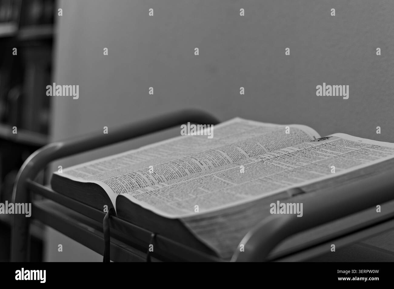 Open dictionary resting on a reading stand in a quiet indoor study setting, showing printed definitions and supporting language learning and reference Stock Photo