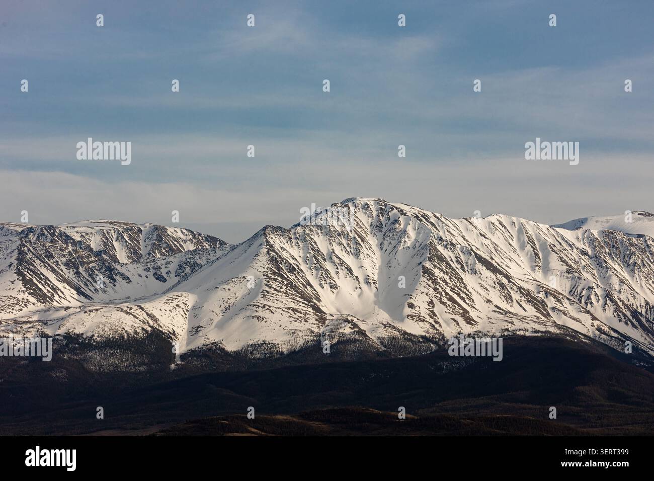 Snow covered mountain range under dramatic cloudy sky Stock Photo