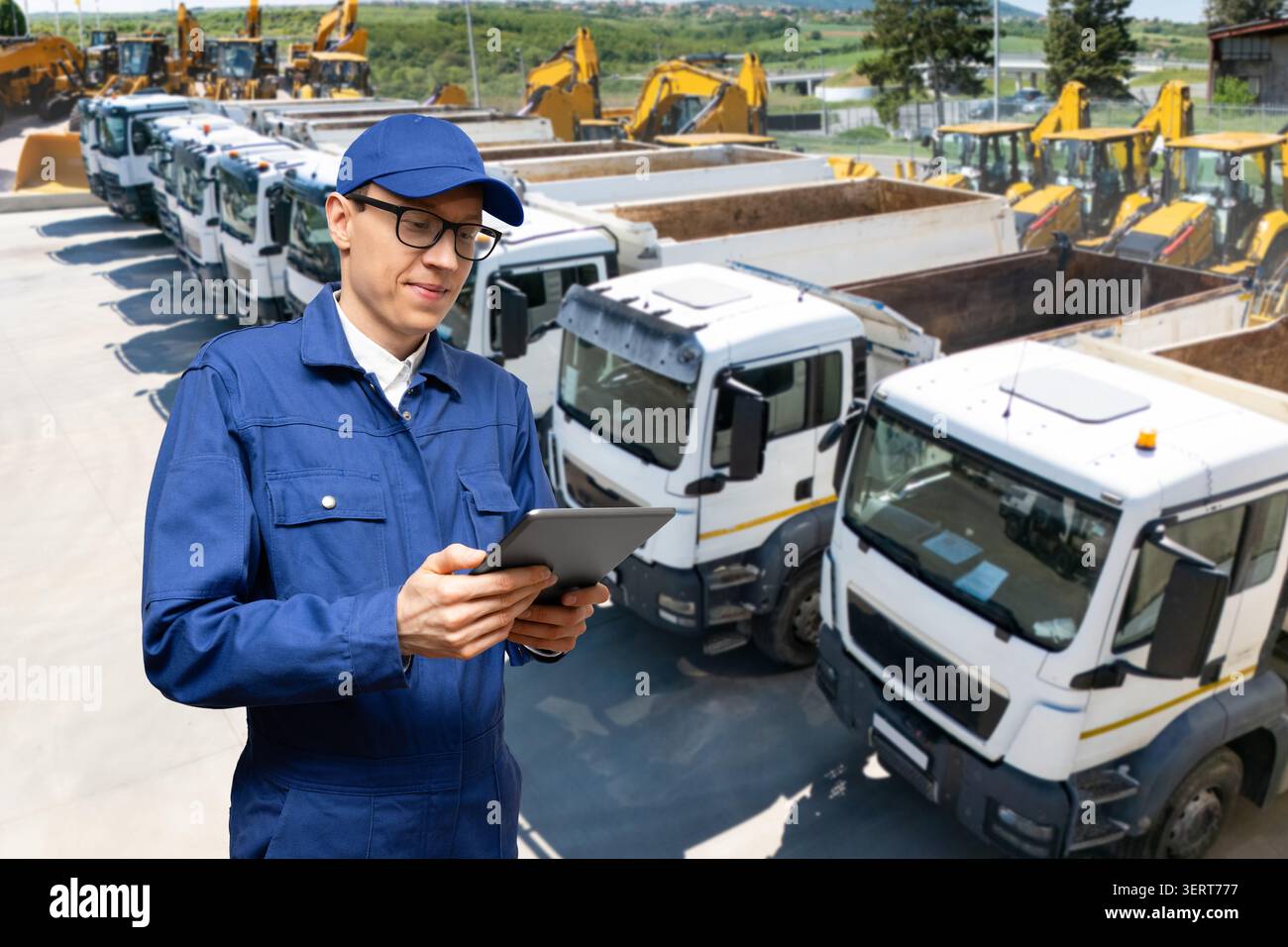 Engineer or site manager using a digital tablet with heavy machinery in the background Stock Photo