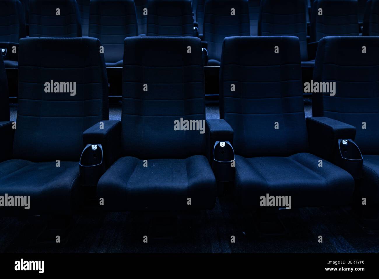 Empty dark rows of blue cinema seats in auditorium Stock Photo