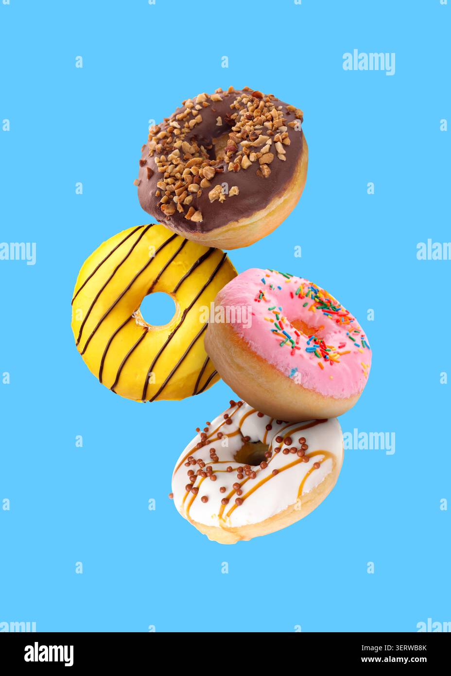 Tasty donuts covered with icing falling on blue background Stock Photo