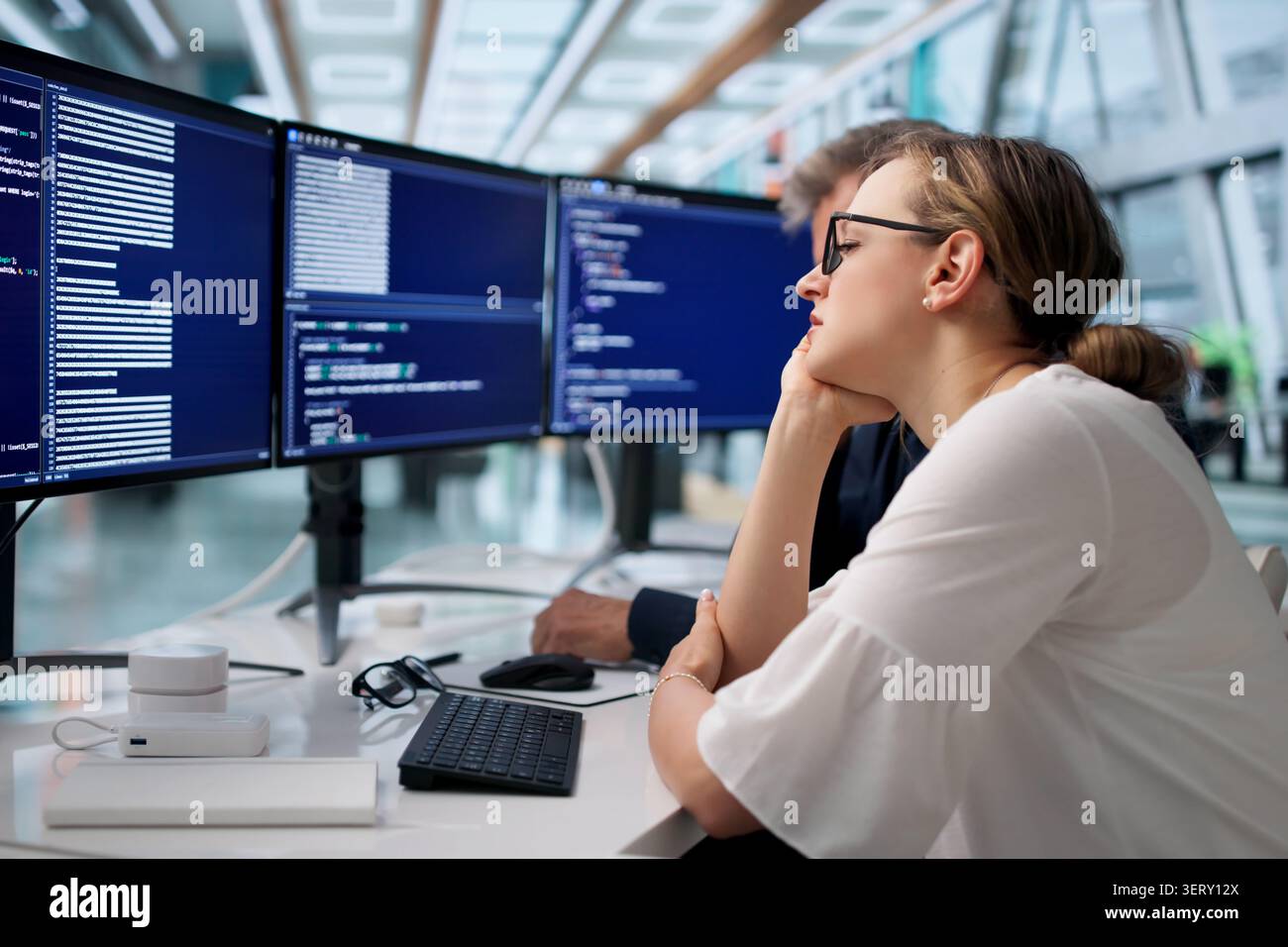 Frustrated Developers Working Late On Broken Code In Quiet Office Space. Stock Photo