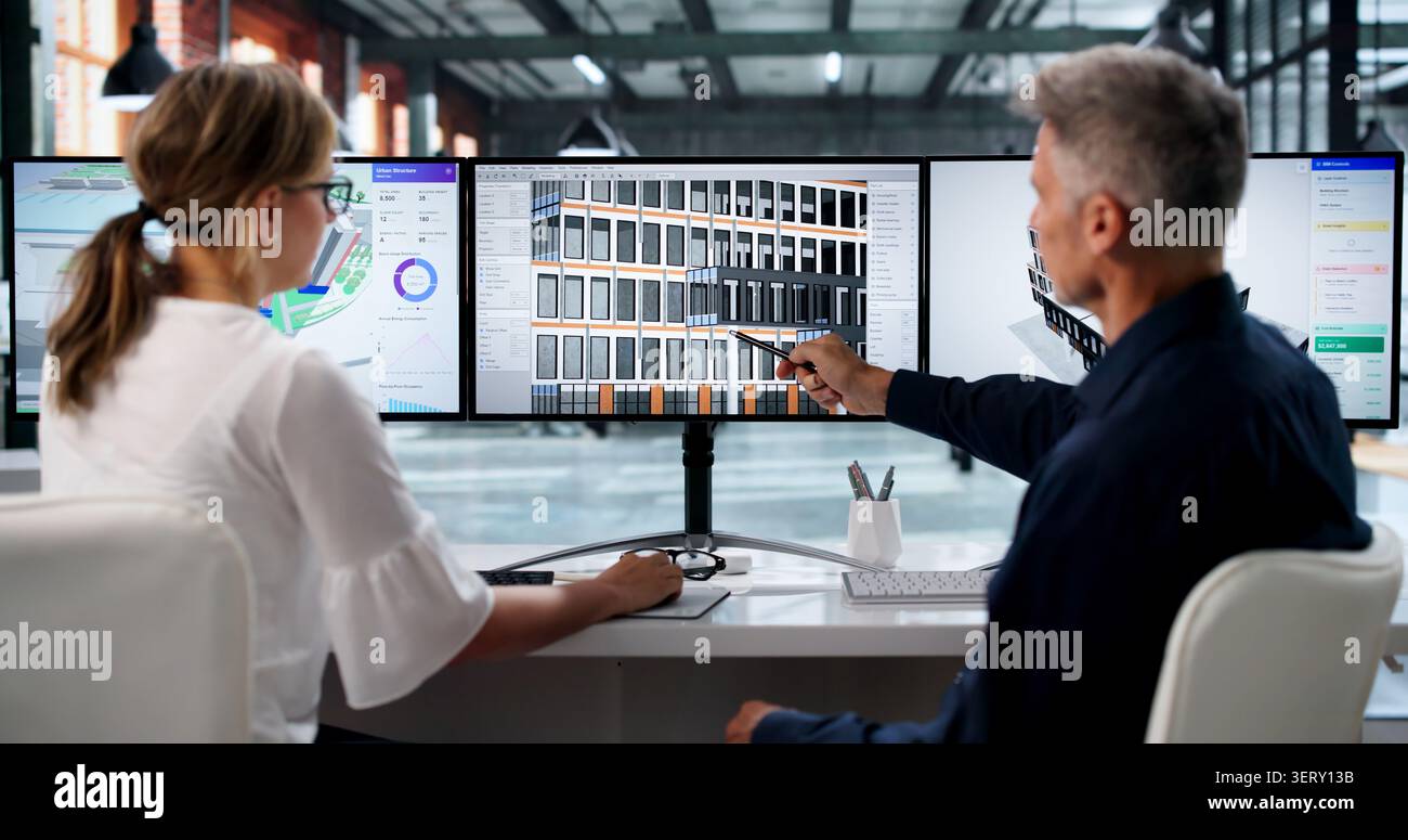 Two Engineers Discuss 3D Building Design Using BIM Software On Computer Screen. Stock Photo