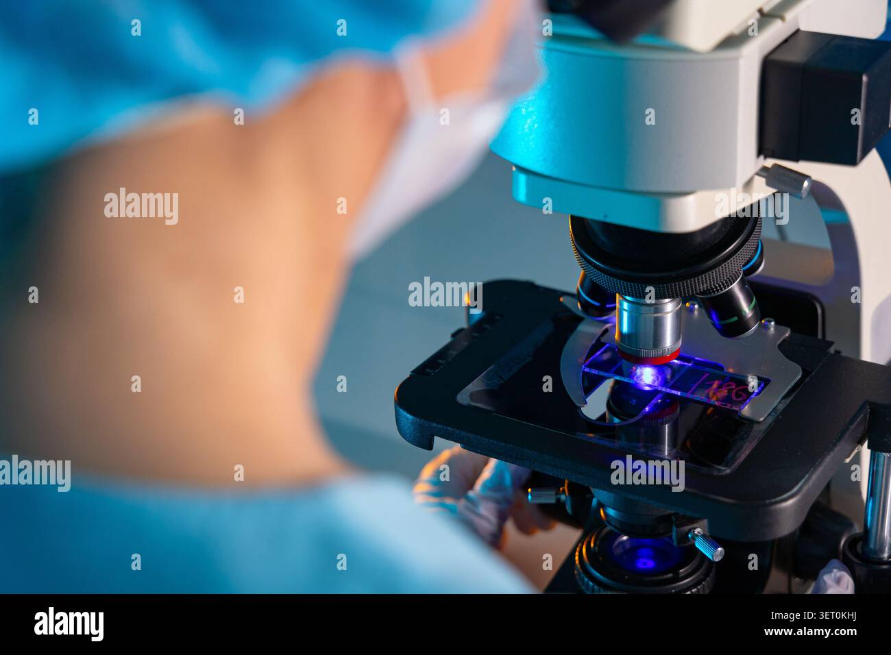 Scientist Examining Sample Through Microscope in Modern Laboratory Stock Photo