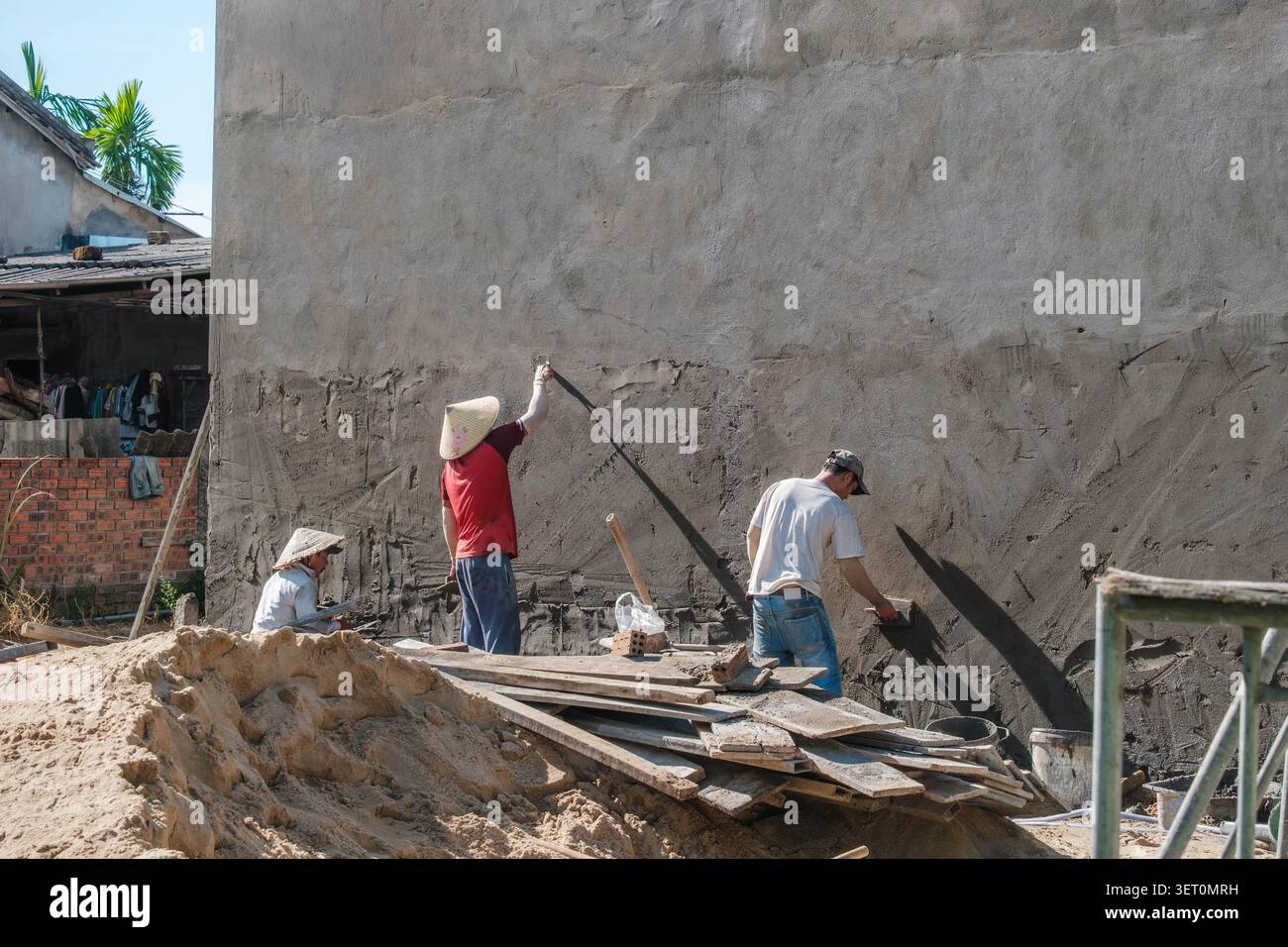 Construction workers plastering a high concrete building wall Stock Photo