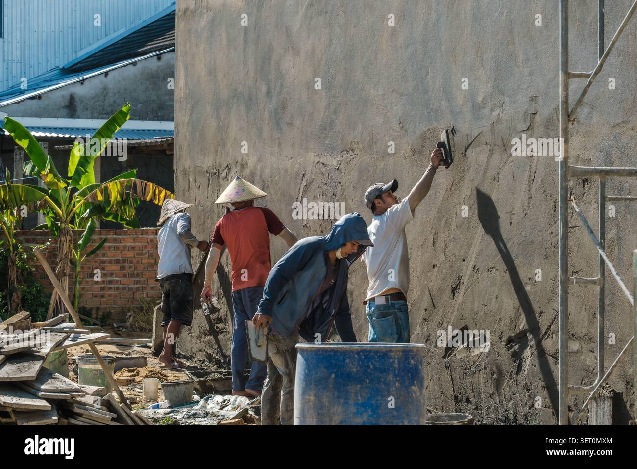 Construction workers plastering a high concrete building wall Stock Photo
