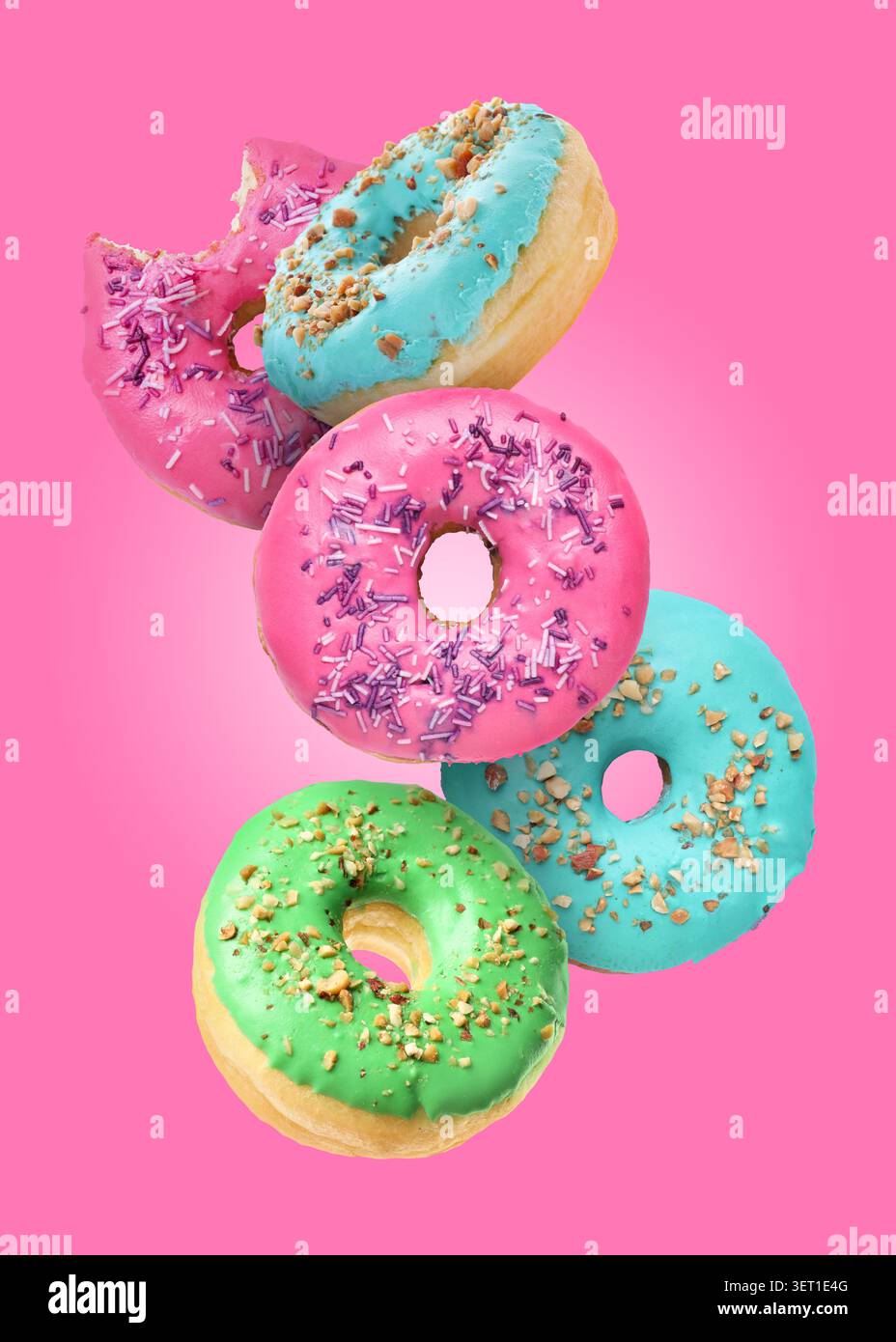 Tasty donuts covered with icing falling on pink background Stock Photo