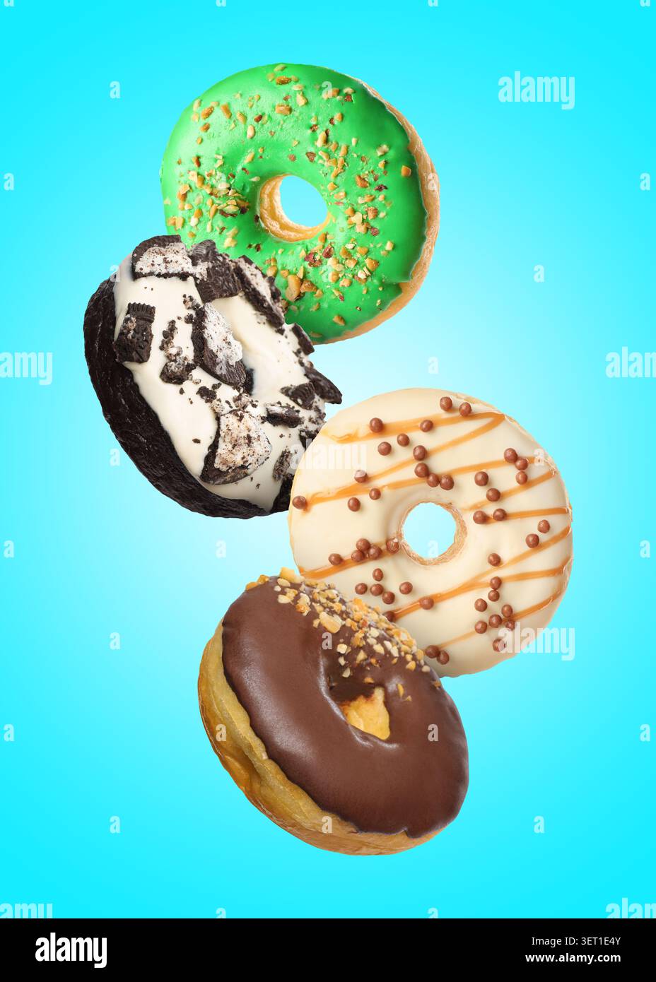 Tasty donuts covered with icing falling on light blue background Stock Photo