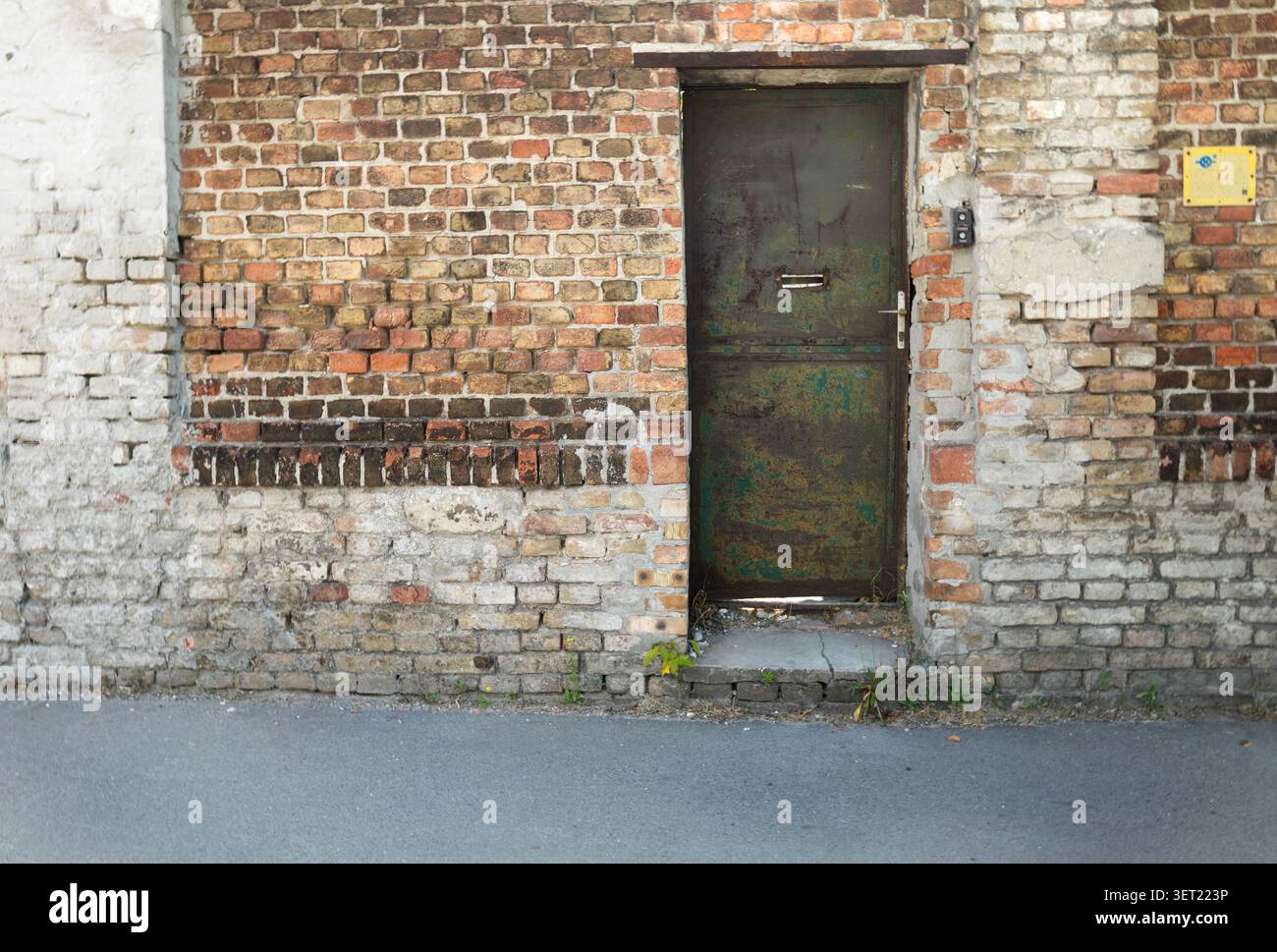 Old rusty metal door in a brick wall Stock Photo
