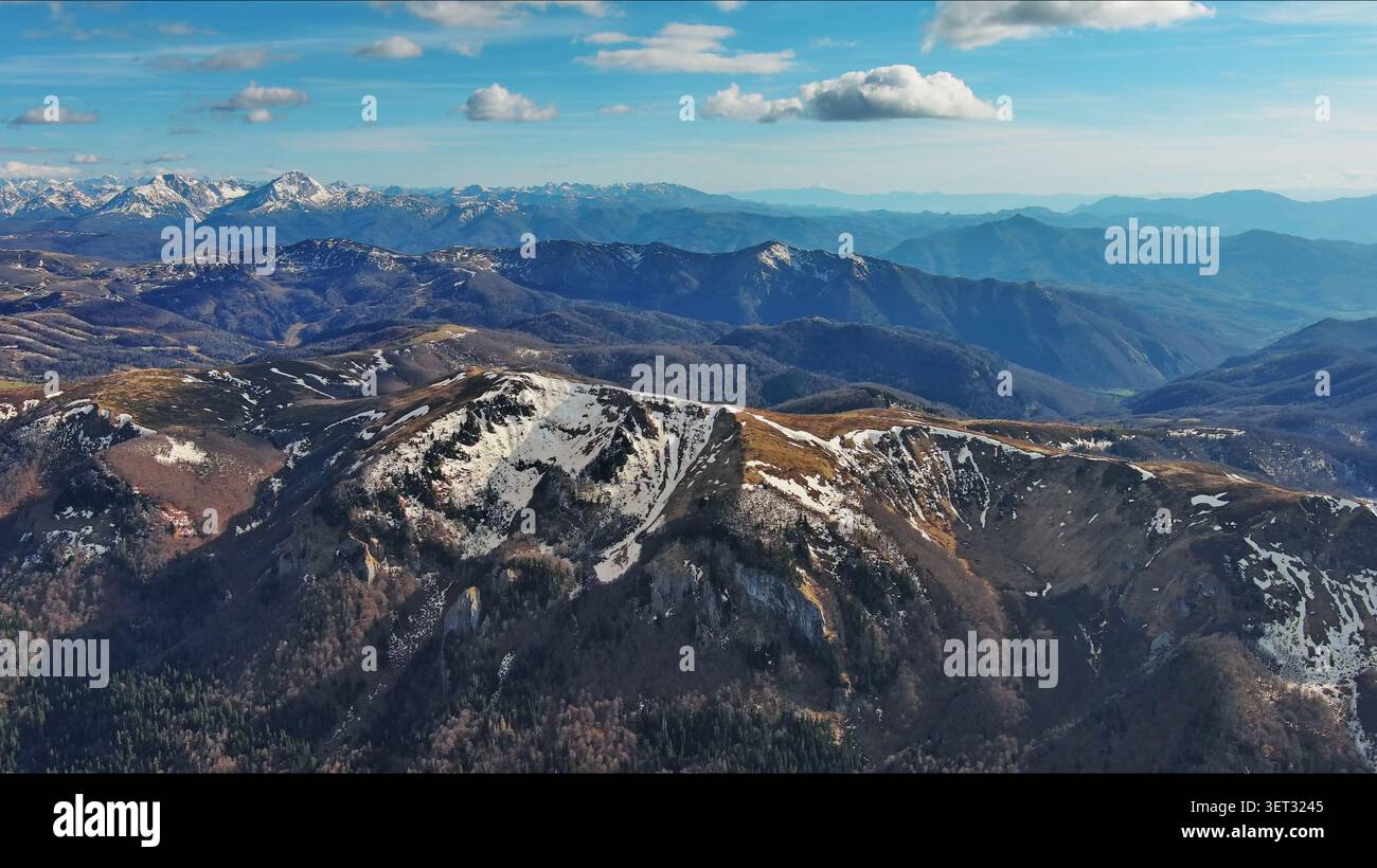 Snow capped mountains under blue sky in spring Stock Photo