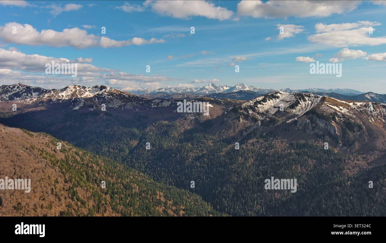 Snow capped mountains under blue sky in spring Stock Photo