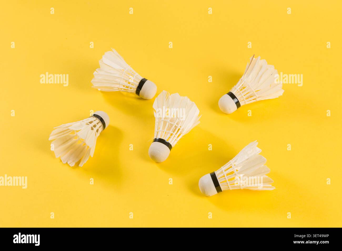 Badminton shuttlecocks lying on a bright yellow surface ready for play Stock Photo