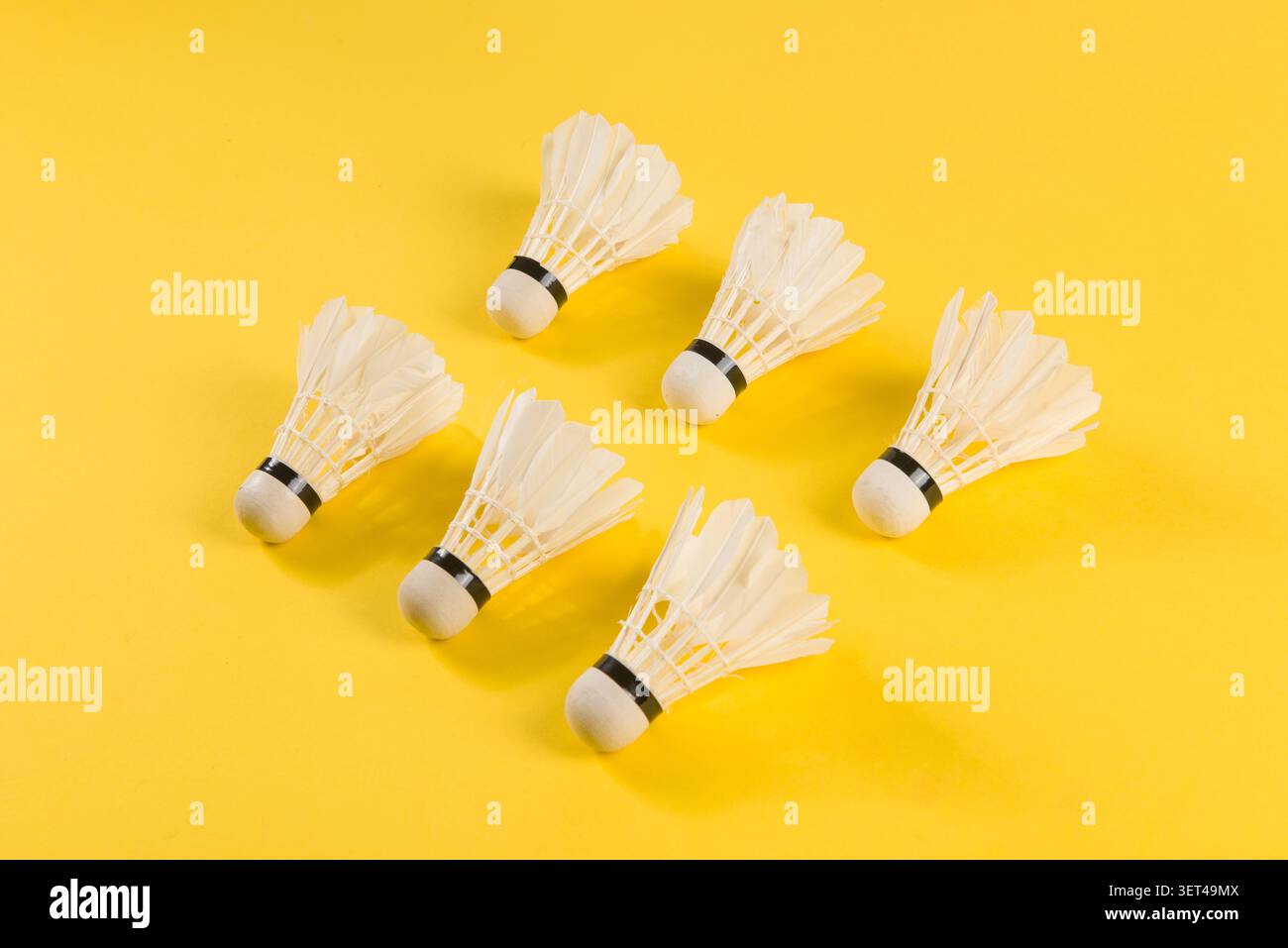 Badminton shuttlecocks lying on a bright yellow surface ready for play Stock Photo