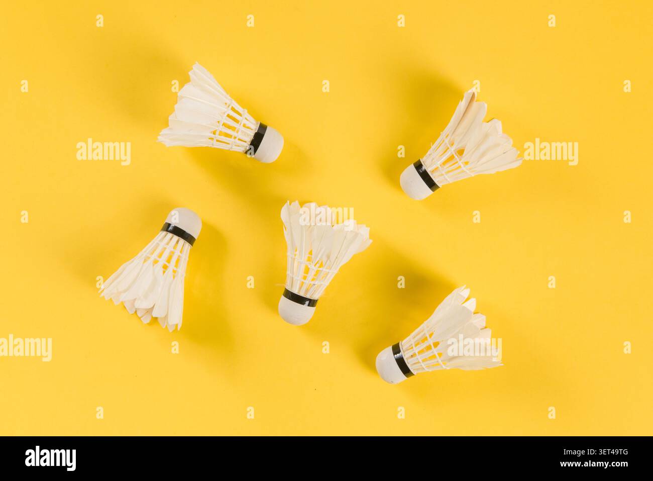 Badminton shuttlecocks lying on a bright yellow surface ready for play Stock Photo
