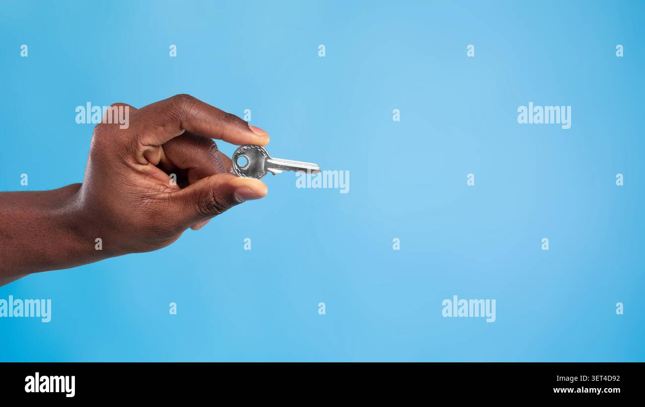 Hand Holding Key, Unrecognizable Person, Blue Background, Security Concept Stock Photo
