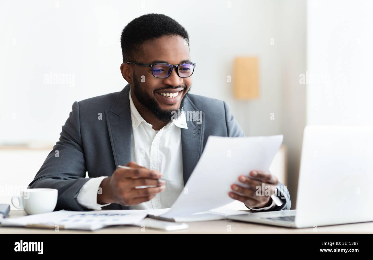 Cheerful black businessman checking reports and making notes Stock Photo
