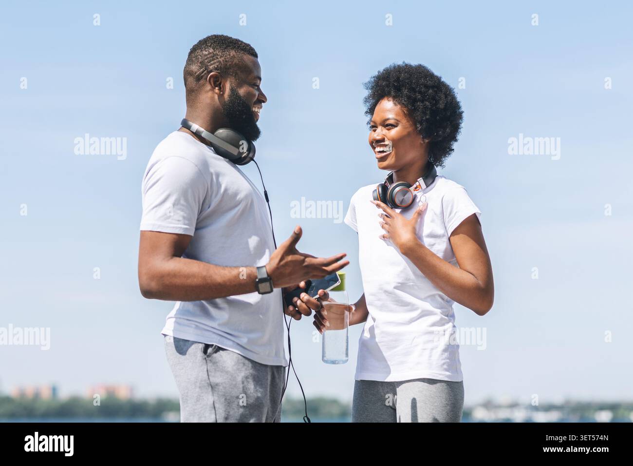 African American Woman Discussing Jogging Program With Coach Outside Stock Photo