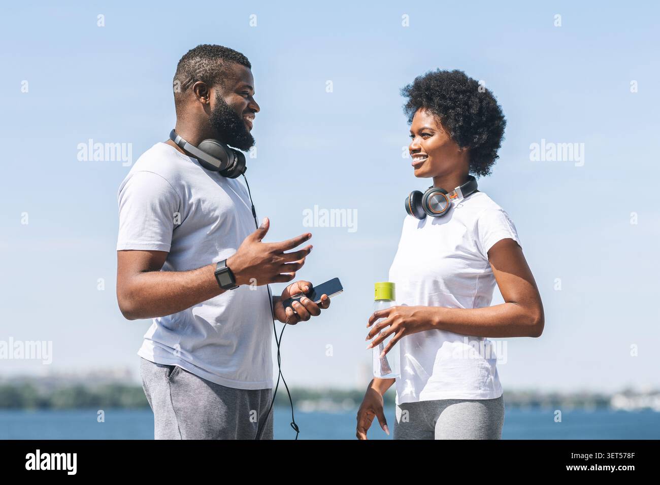 Black Couple Talking Before Morning Jog Along River Bank Stock Photo