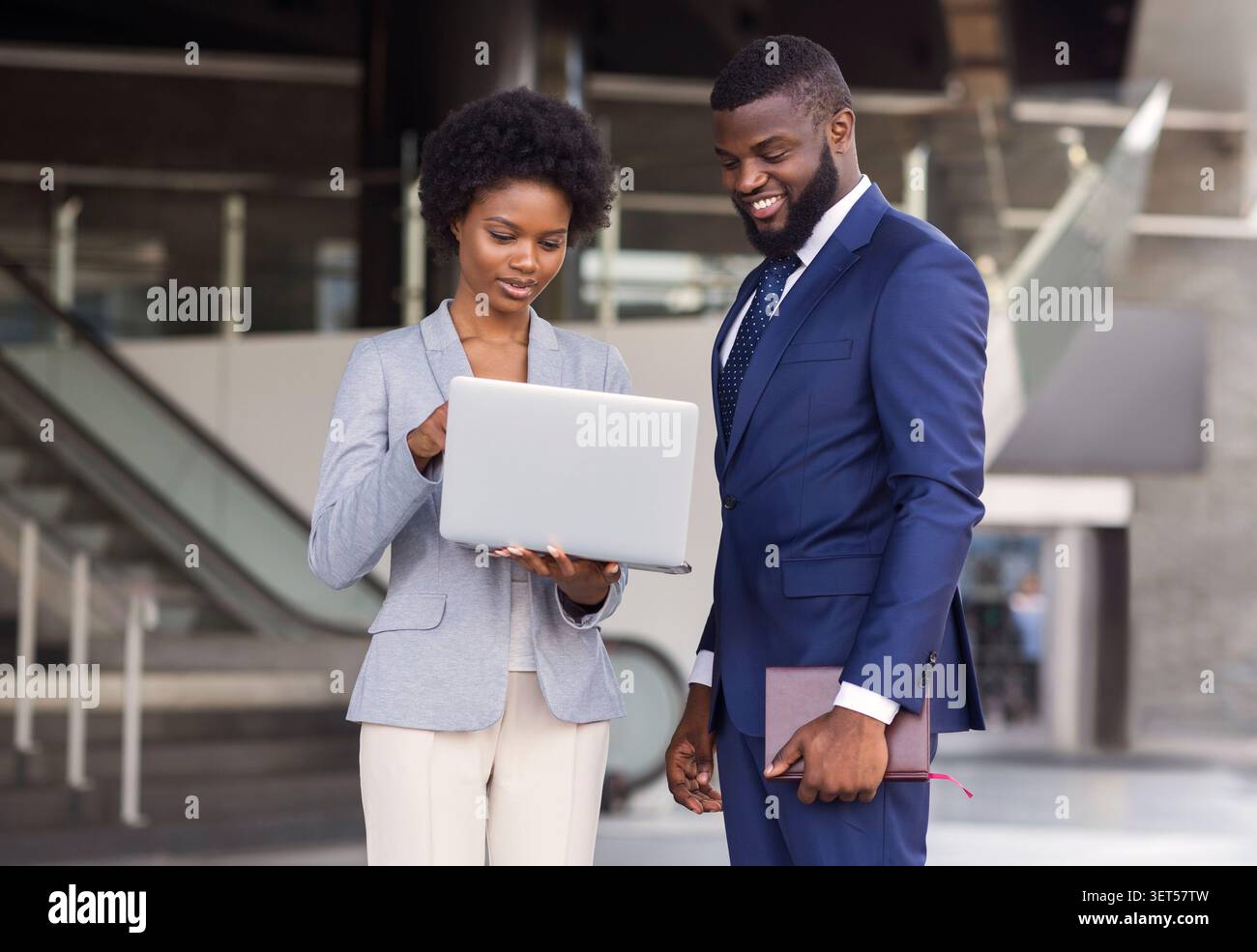 Young woman pointing finger to laptop screen while standing outdoors Stock Photo