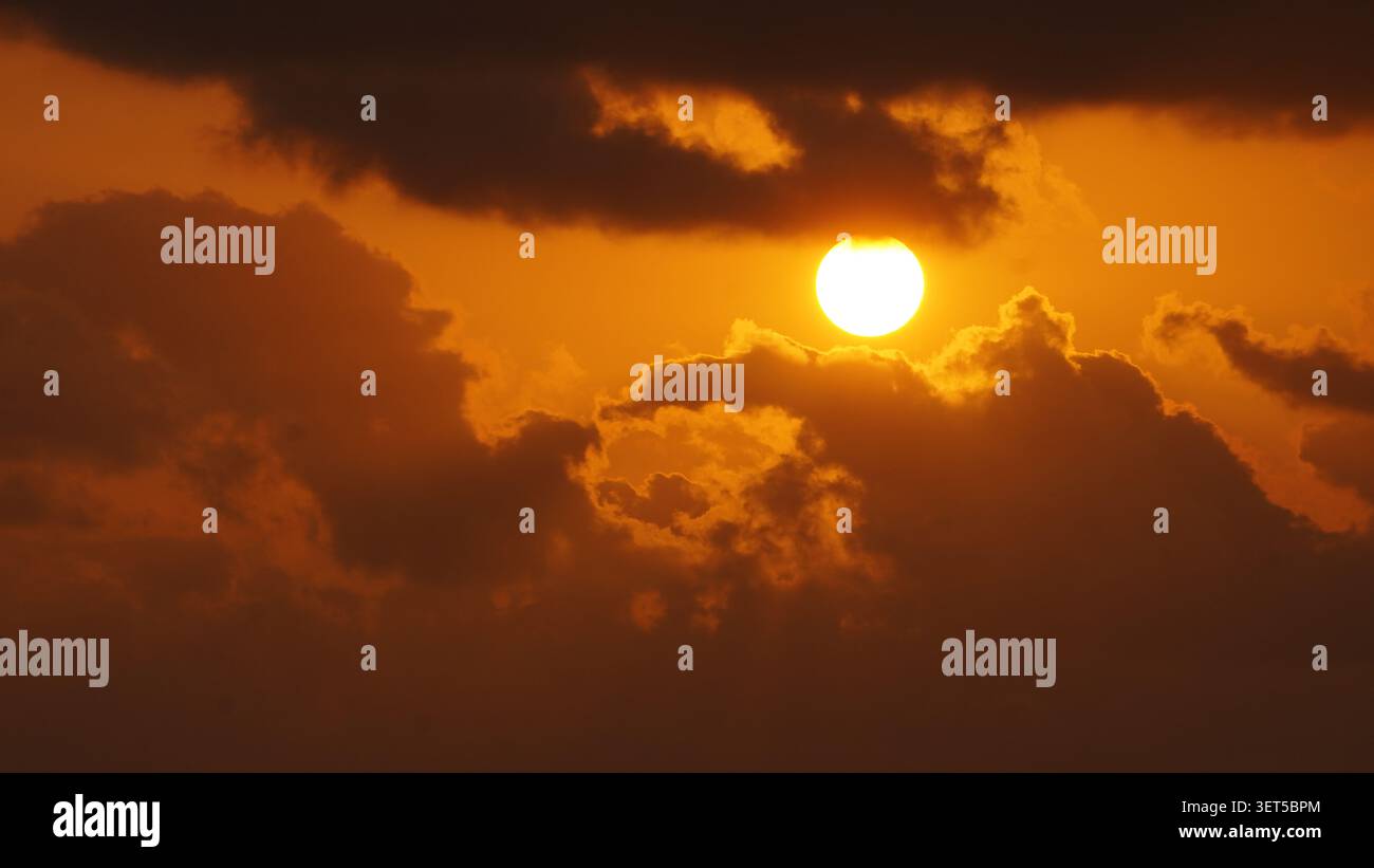 Golden sunset shining through dramatic clouds in the evening sky. Stock Photo