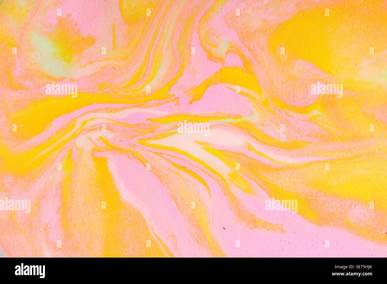 Fluid acrylic painting creating a colorful abstract background with swirling pink and yellow Stock Photo
